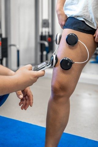 the procedure of myostimulation on the legs of a woman.